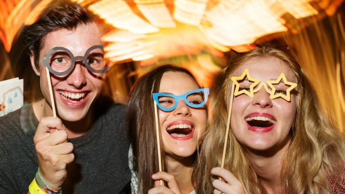 Groupe d'amis souriant avec des accessoires amusants lors d'une fête.